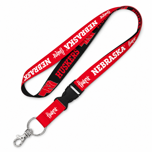A red and black Nebraska Huskers lanyard with a silver clasp, featuring the Nebraska 'N' logo and 'HUSKERS' text printed on the webbed strap.